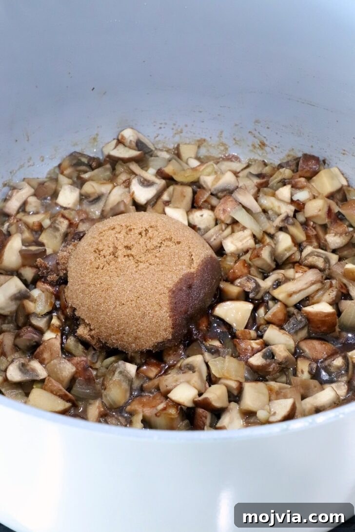 Savory Mushroom Jam Recipe for Spreading and Cooking 9 cooked diced mushrooms in a pot on the stove with brown sugar