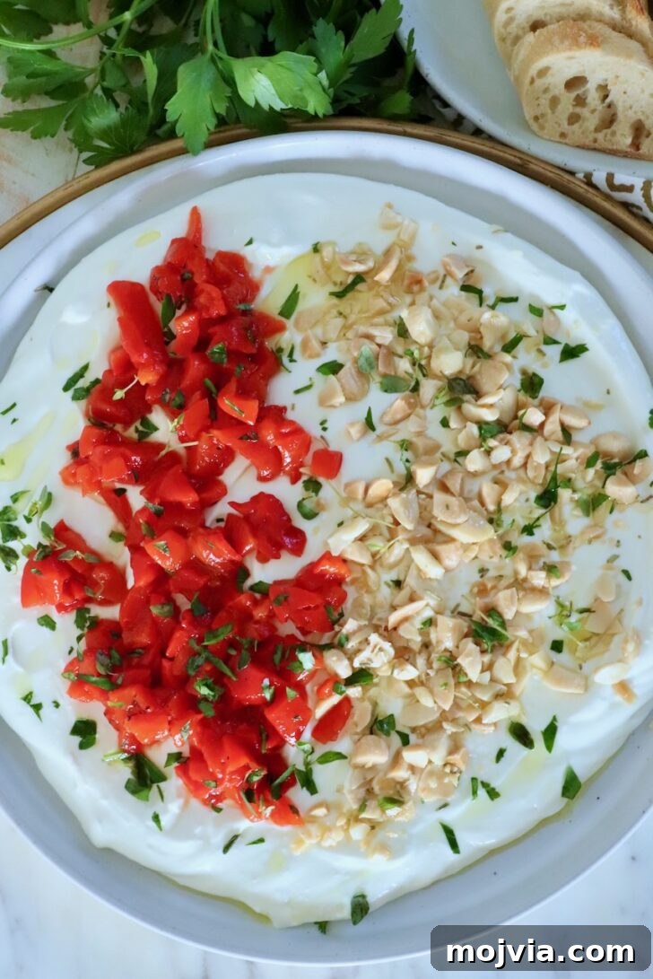 Whipped Goat Cheese Dip Recipe for Entertaining and Snacks 9 whipped goat cheese dip on a rimmed plate topped with chopped almonds, roasted red peppers and fresh herbs