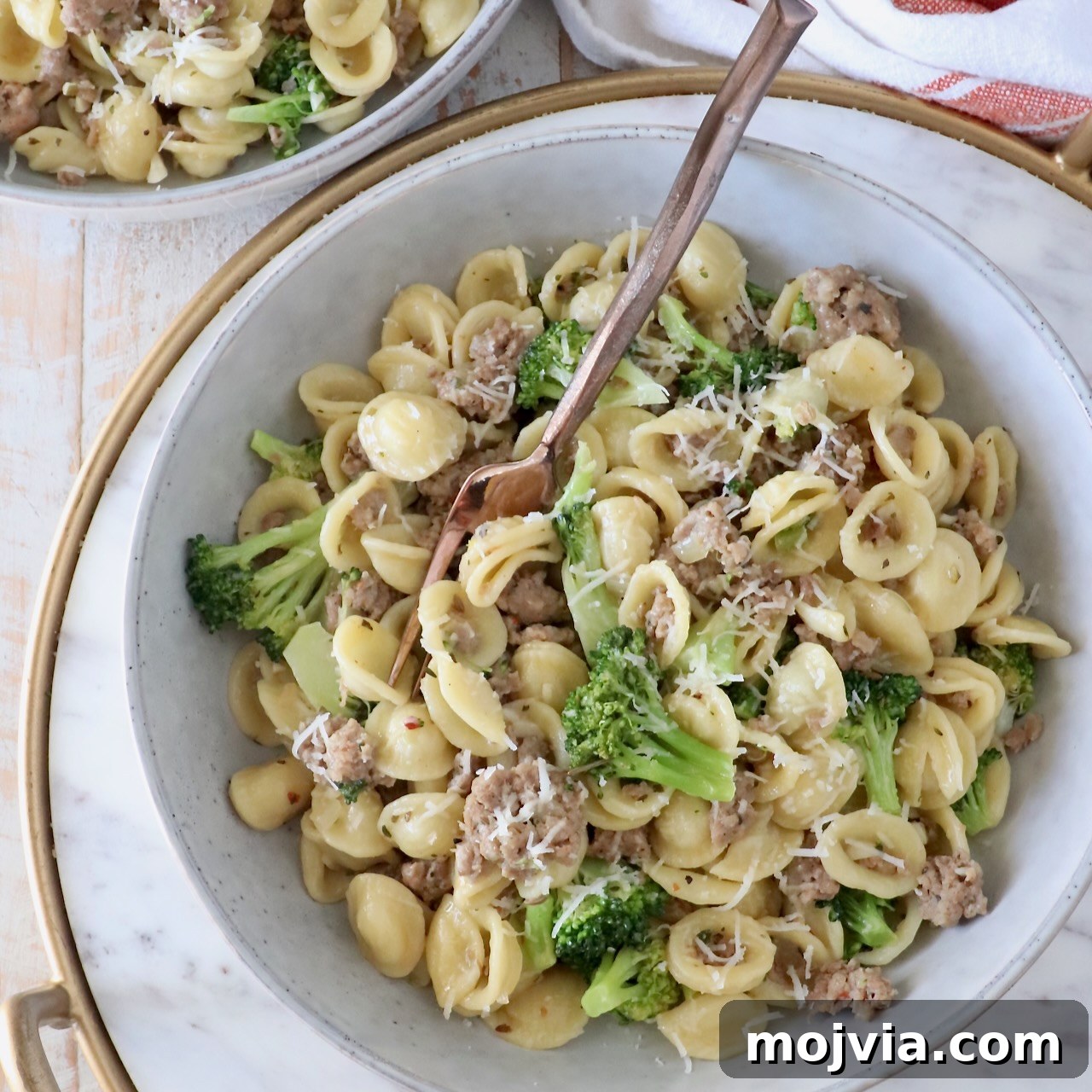 cooked orecchiette pasta with broccoli and Italian sausage in a bowl with a fork