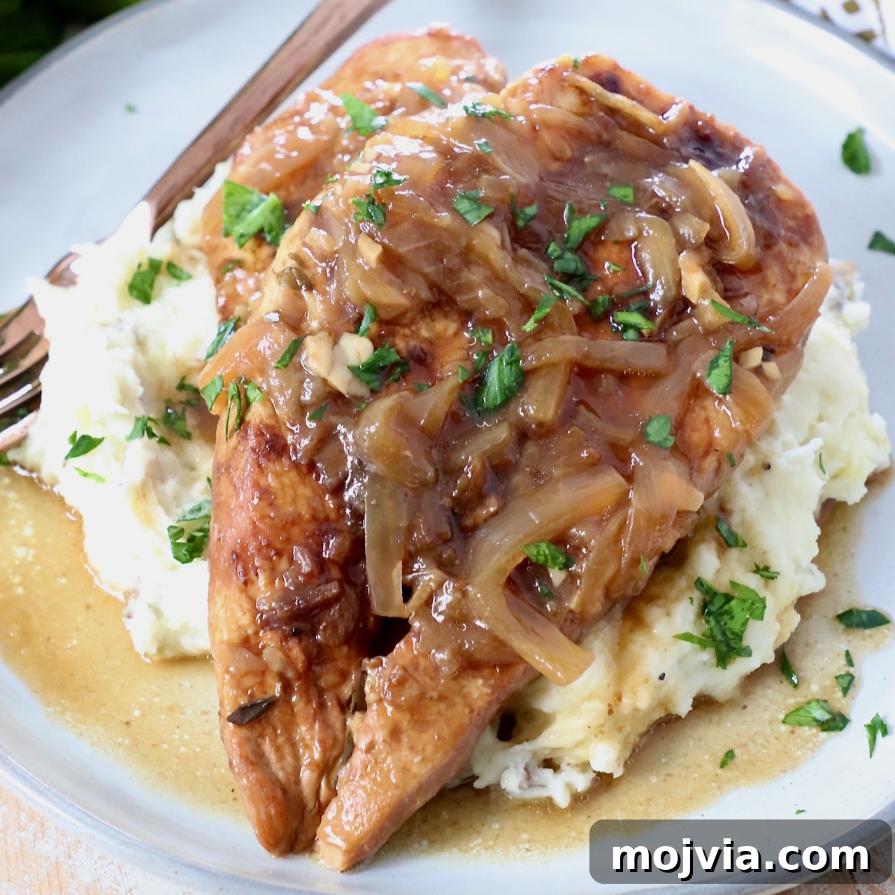 cooked french onion chicken breasts on plate with mashed potatoes