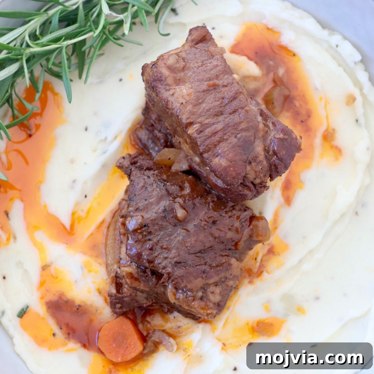 braised short ribs in bowl with mashed potatoes and fresh rosemary