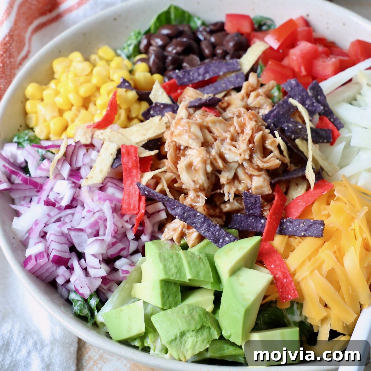 salad in bowl topped with shredded bbq chicken and vegetables