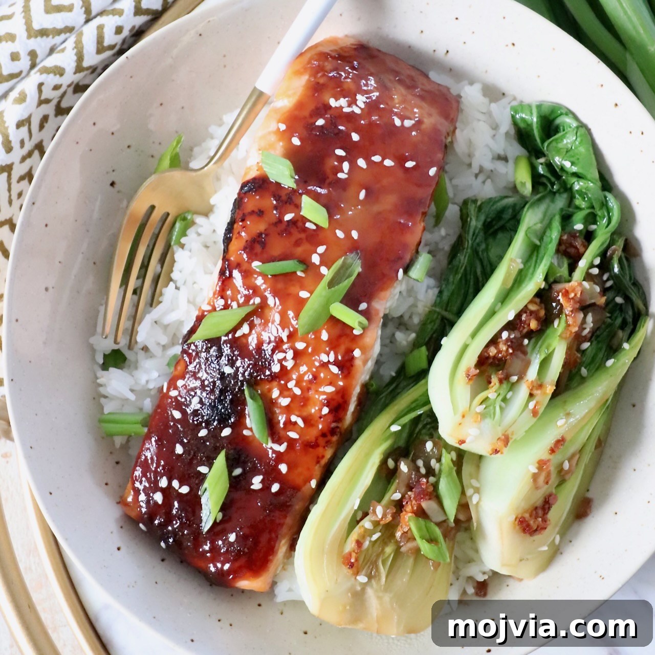 filet of cooked miso glazed salmon in bowl with fork and baby bok choy