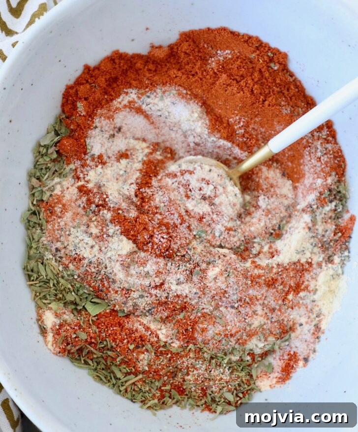 dried herbs and spices mixed together in a bowl with a spoon