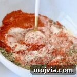 dried herbs and spices combined in a bowl with a spoon