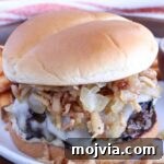 French Onion Burger Recipe with Caramelized Onions & Gruyère 11 french onion burger on a plate topped with crispy onions and caramelized onions