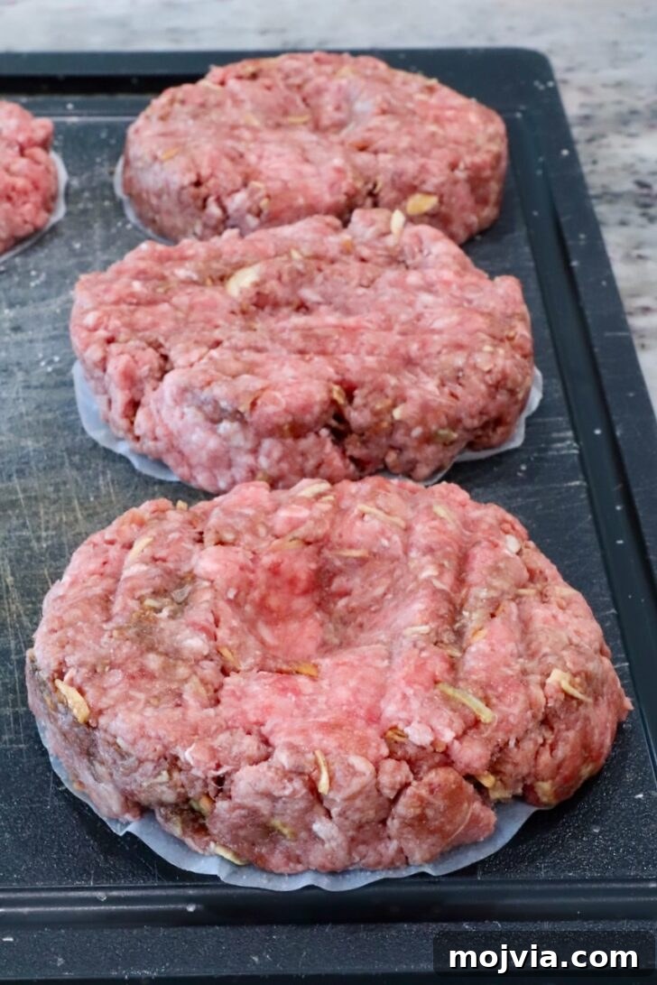 French Onion Burger Recipe with Caramelized Onions & Gruyère 6 raw burger patties on a cutting board