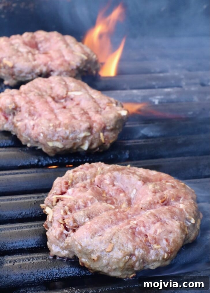 French Onion Burger Recipe with Caramelized Onions & Gruyère 7 burger patties on a grill