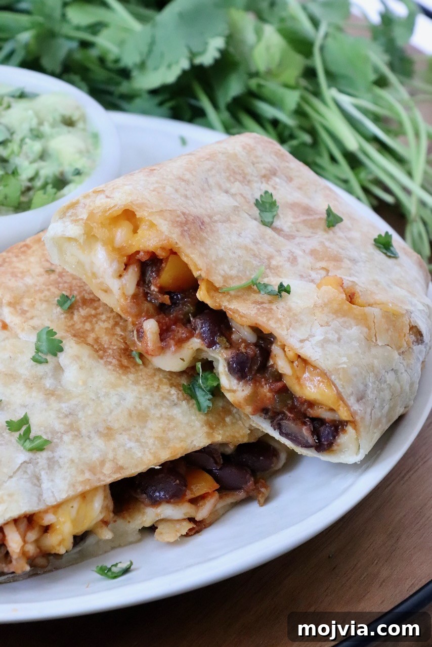 Melted Cheese, Beans & Rice Burrito Recipe for Weeknights 2 bean and cheese burrito cut in half and stacked up on a plate with a bowl of guacamole and fresh cilantro in the background