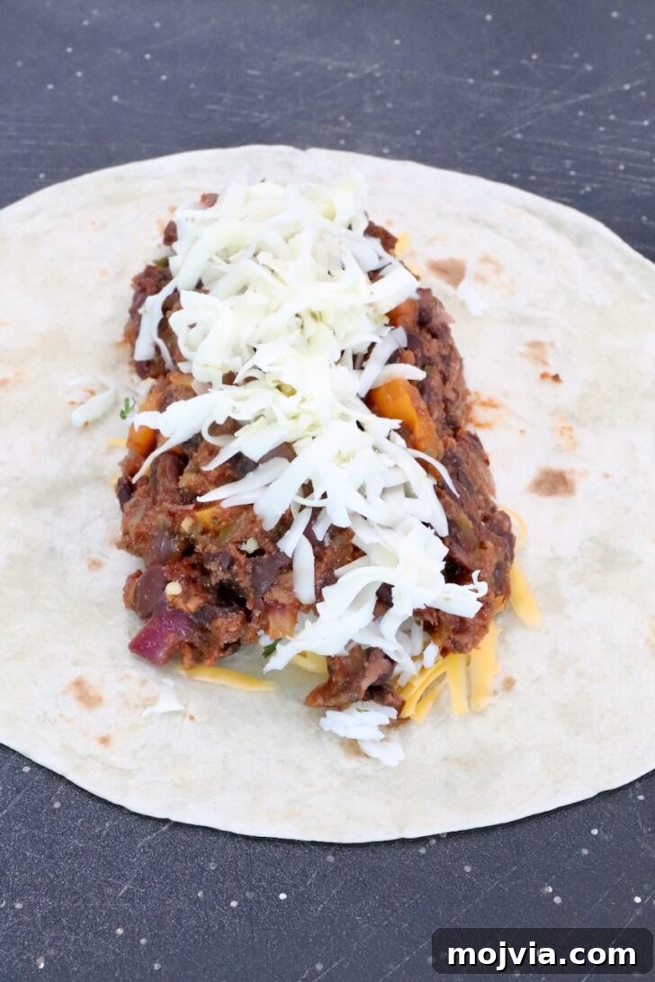 Melted Cheese, Beans & Rice Burrito Recipe for Weeknights 11 bean filling in the middle of a tortilla topped with shredded pepper jack cheese