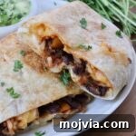 Melted Cheese, Beans & Rice Burrito Recipe for Weeknights 17 bean and cheese burrito cut in half and stacked up on each other on a plate
