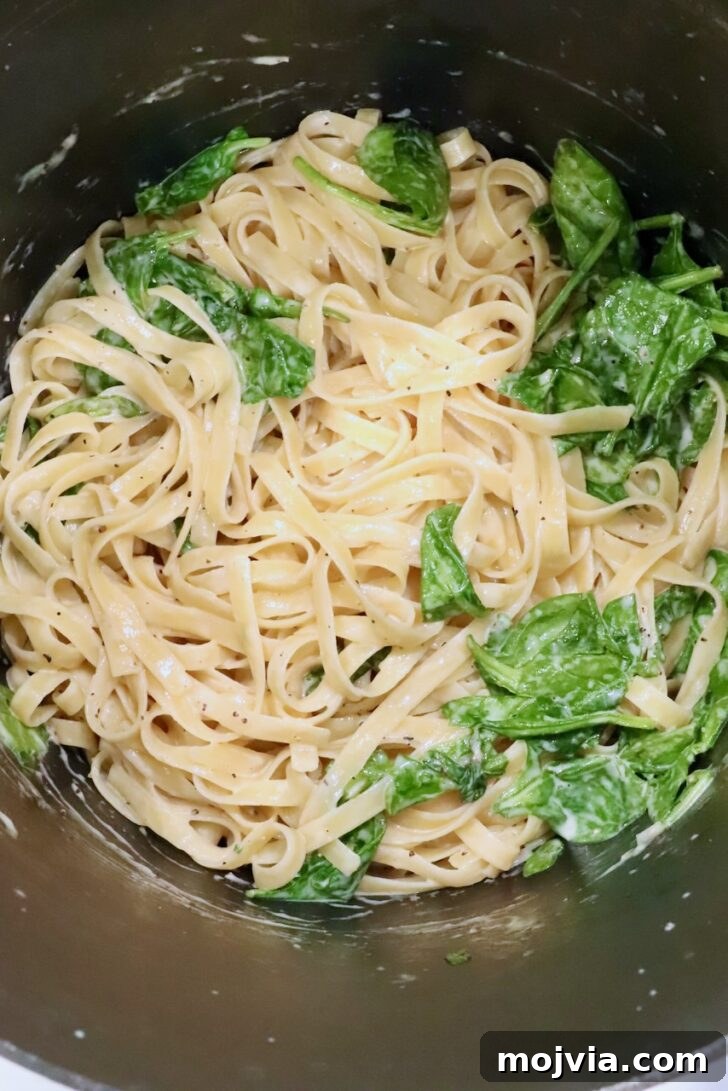 Creamy Chicken Caesar Pasta Recipe for Weeknight Dinners 11 pasta noodles in a large pot tossed with a creamy sauce and spinach