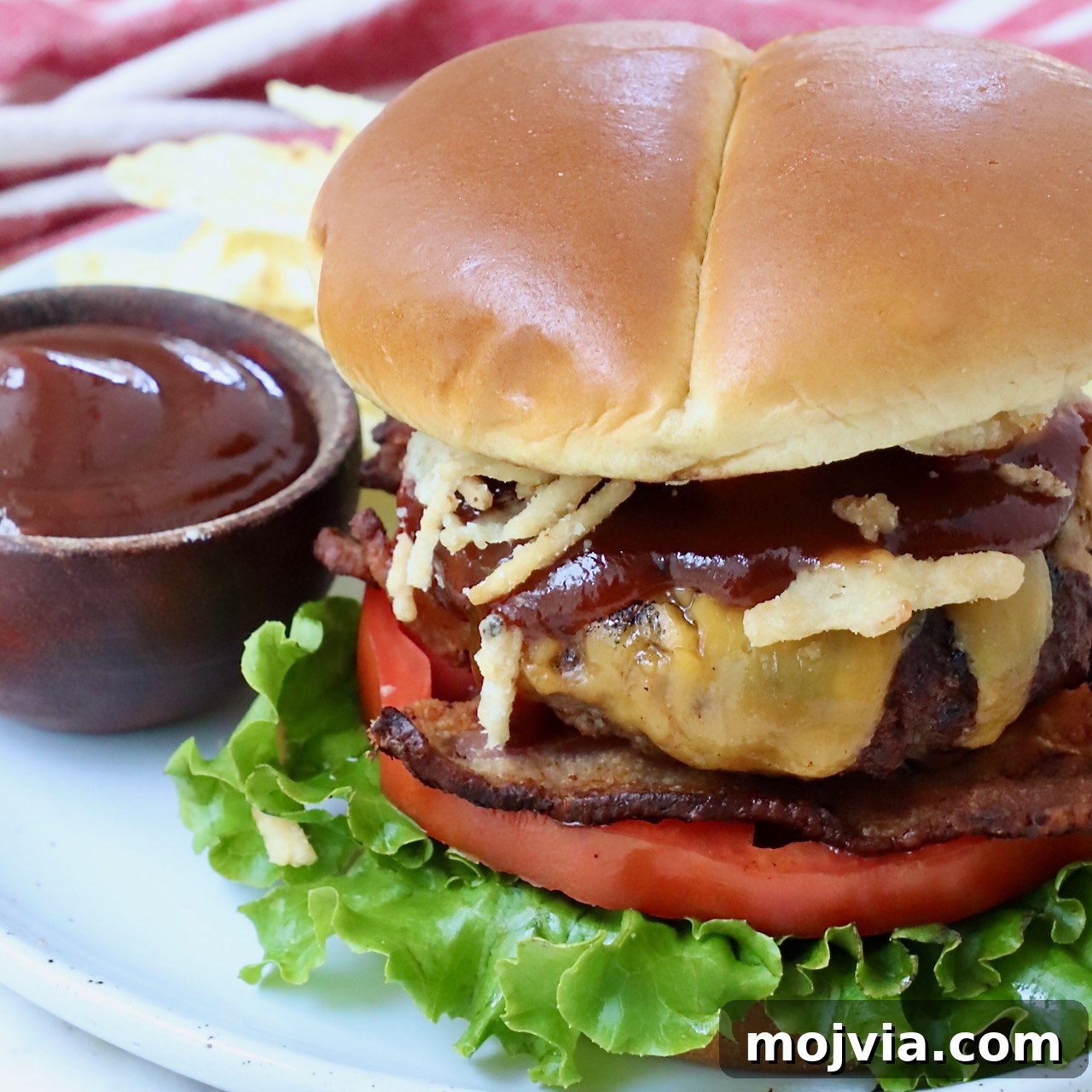Complete Burger Guide: Techniques, Recipes & Toppings for Perfect Patties 16 cooked cheeseburger on plate with a side bowl of bbq sauce