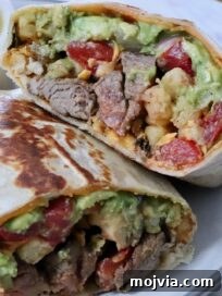 Authentic California Burrito Recipe with Carne Asada and Fries 12 california burrito filled with carne asada and french fries cut in half and stacked up on a plate with a bowl of green salsa in the background