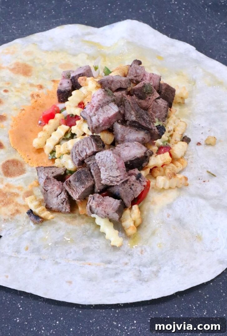 Authentic California Burrito Recipe with Carne Asada and Fries 8 carne asada and french fries on top of pico de gallo in the middle of a tortilla