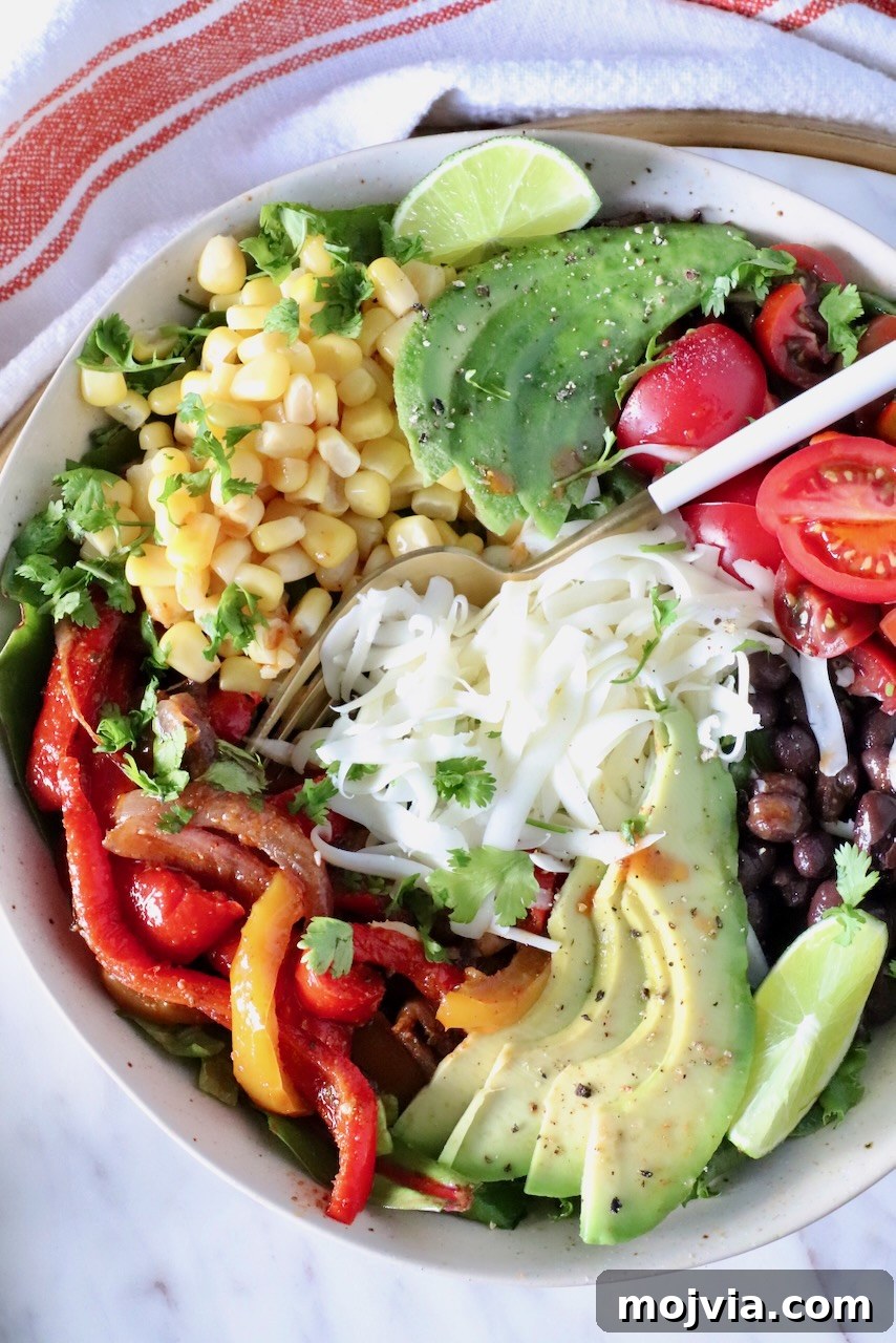 Smoky Chipotle Salad with Avocado and Corn 2 chipotle salad in a bowl topped with fajita veggies, cheese, avocado, corn, and tomatoes