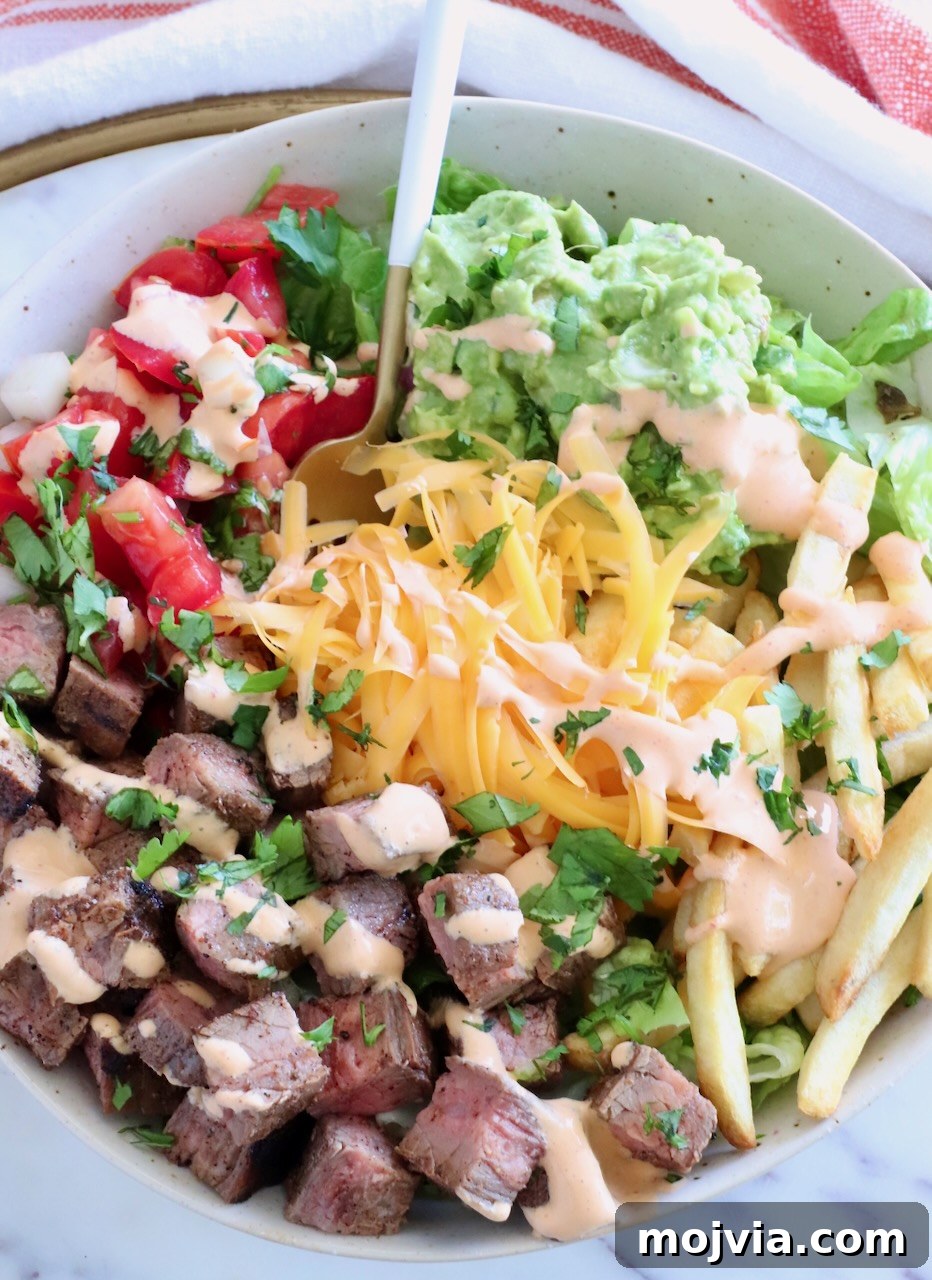 California Burrito Bowl with Carne Asada and Avocado 2 bowl filled with diced carne asada, shredded cheese, guacamole, and pico de gallo with a fork in the middle