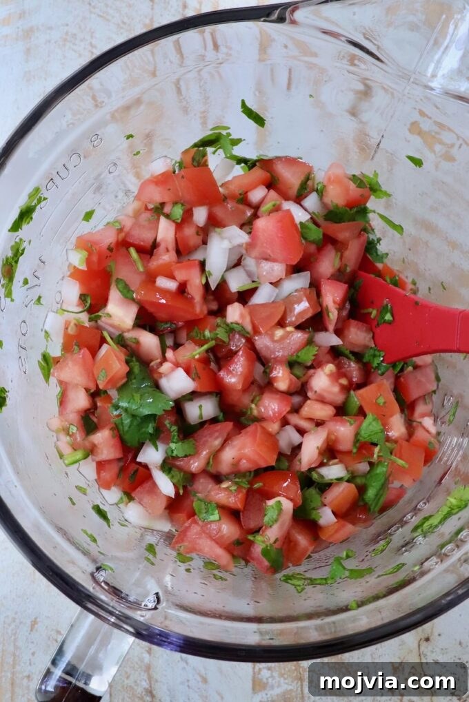 California Burrito Bowl with Carne Asada and Avocado 8 pico de gallo in a glass bowl with a red spatula