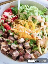 California Burrito Bowl with Carne Asada and Avocado 10 bowl filled with diced carne asada, french fries, cheese, pico de gallo and guacamole, with a fork in the middle