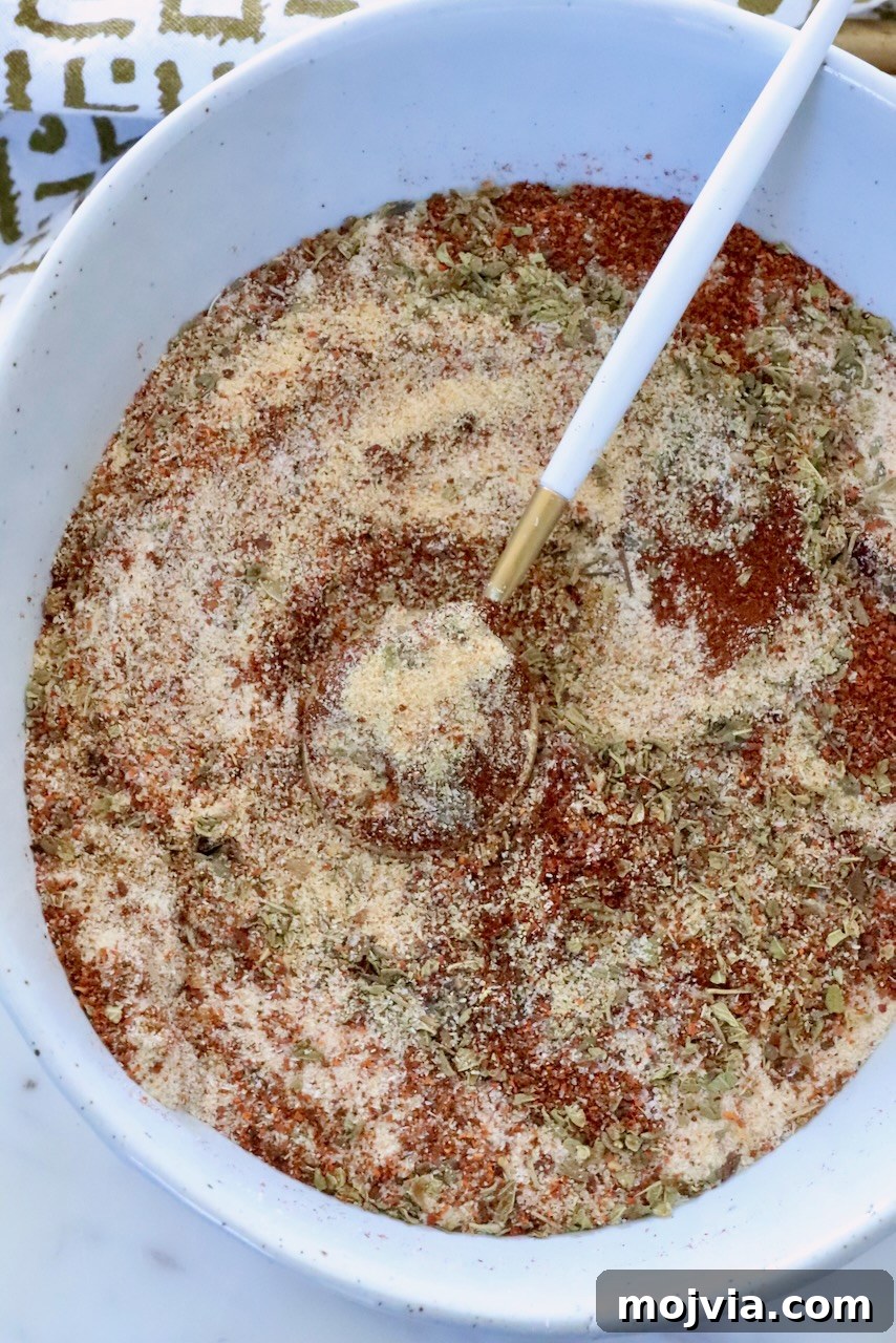 Authentic Barbacoa Seasoning Blend for Tacos and Burritos 2 dried herbs and spices mixed together in a white bowl with a small spoon