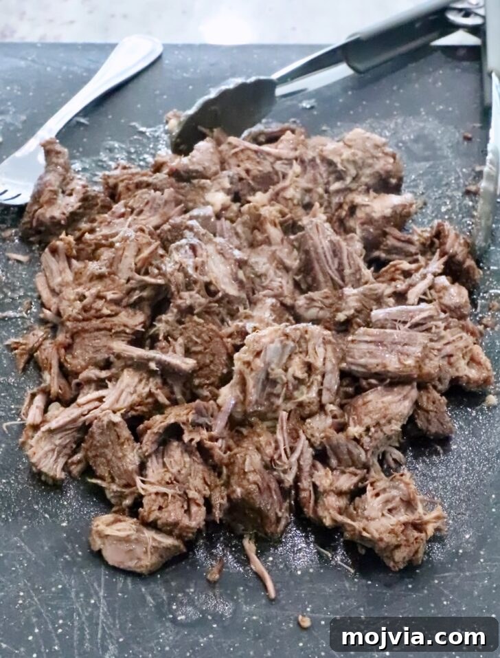 Instant Pot Beef Barbacoa: Tender Mexican Shredded Beef 11 shredded beef on a cutting board