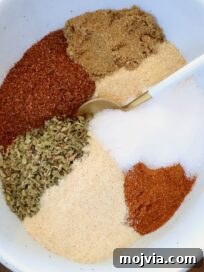 Homemade Chicken Taco Seasoning Mix for Flavorful Tacos 8 dried herbs and spices separated in a bowl with a spoon