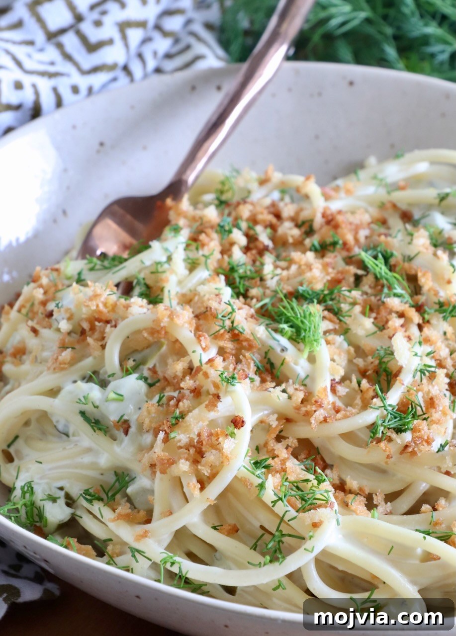 Creamy Dill-Pickle Pasta with Tangy Sauce 2 spaghetti tossed in a creamy sauce in a bowl topped with crunchy breadcrumbs and fresh dill