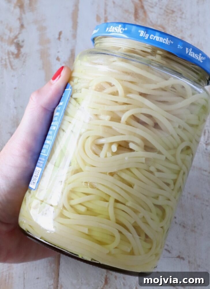 Creamy Dill-Pickle Pasta with Tangy Sauce 6 spaghetti noodles in a jar of pickle juice, with a hand holding the jar