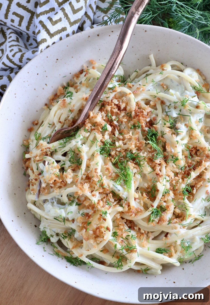 Creamy Dill-Pickle Pasta with Tangy Sauce 9 spaghetti tossed in a creamy sauce topped with breadcrumbs and dill in a bowl with a fork