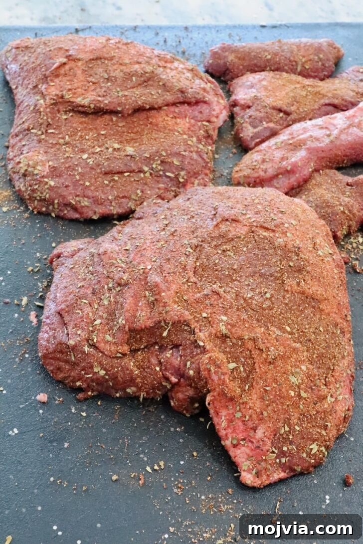 Tender Smoked Beef Cheek Barbacoa Recipe 5 seasoned beef cheeks on a black cutting board