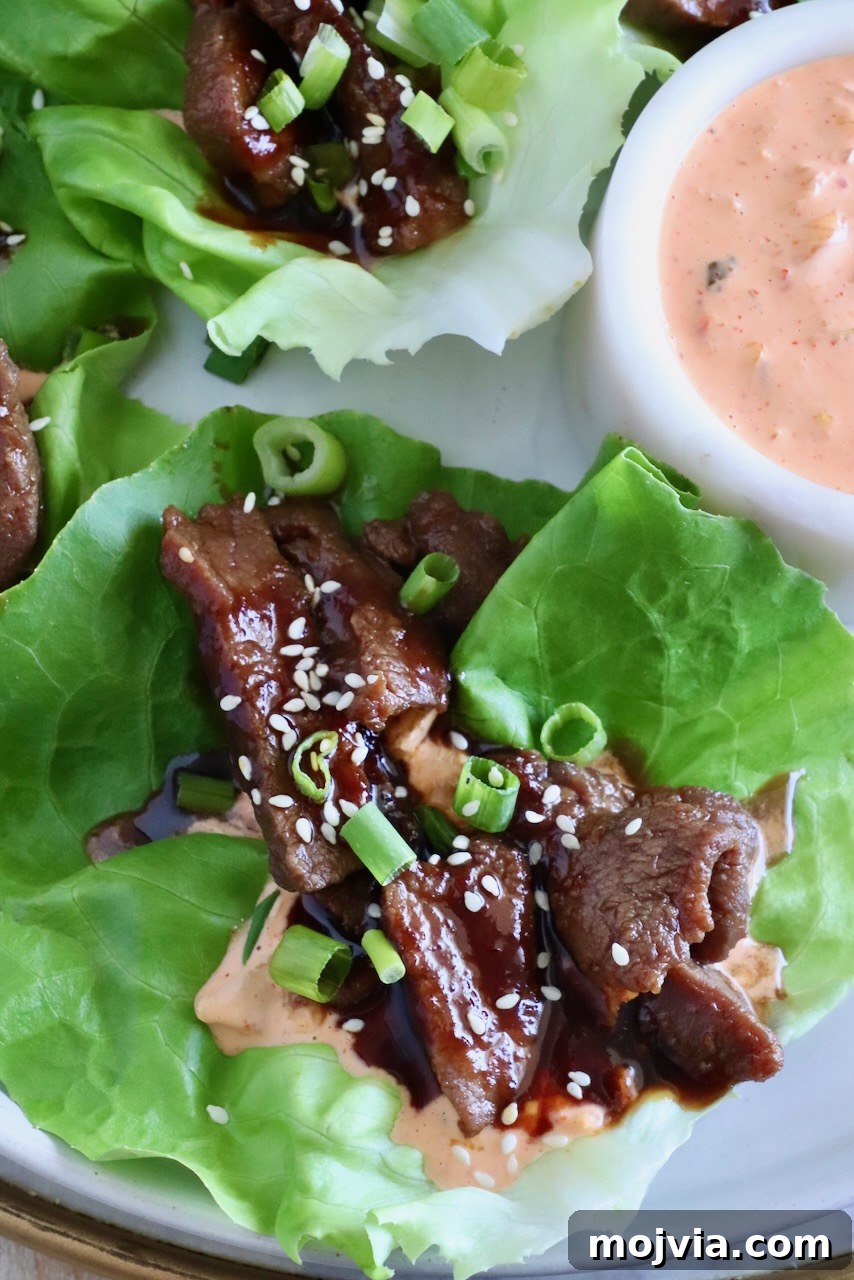 Korean Beef Bulgogi Lettuce Wraps Recipe 2 korean bbq sliced beef in a lettuce wrap with a creamy gochujang sauce on a plate